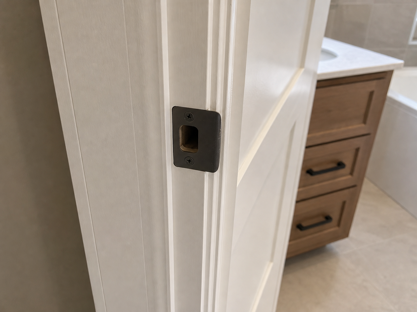 Close-up evidence of a misaligned bathroom door strike plate